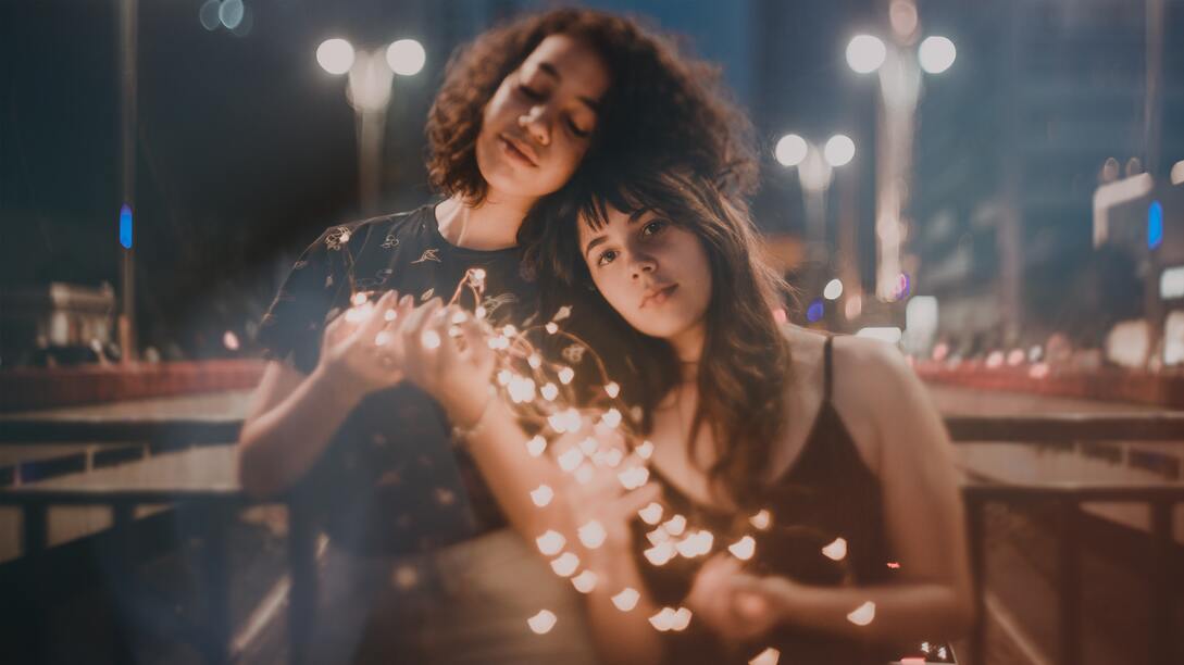 Two friends holding holiday string lights