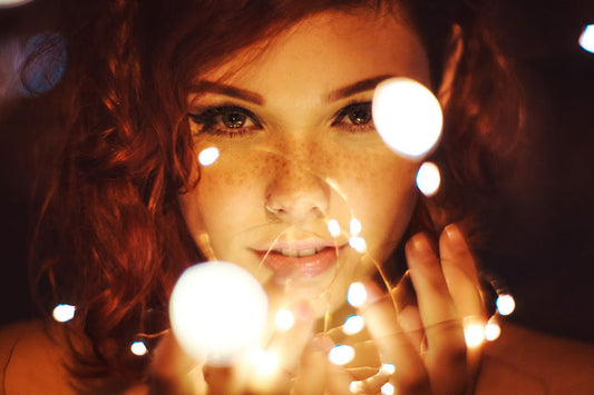Woman’s face illuminated by string lights in her hand