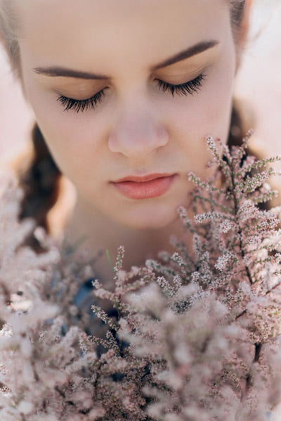 woman with eyes closed surrounded by flowers