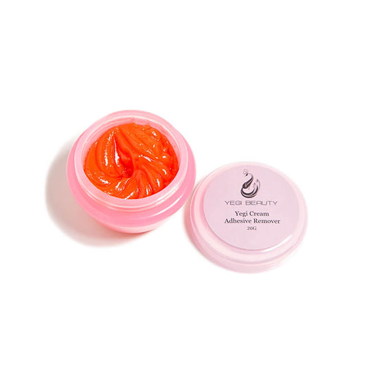20g tiny pink round container with cap off and placed to the side revealing orange cream inside. Cap label reads "Yegi Cream Adhesive Remover." Product against white table top