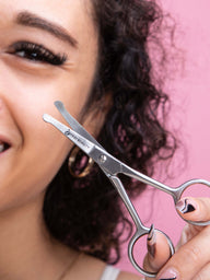 Safety scissors held by woman with eyelash extensions. 